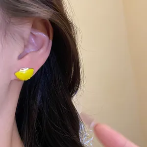 Detailed shot of yellow enamel starfish stud earrings with silver needles on an ear