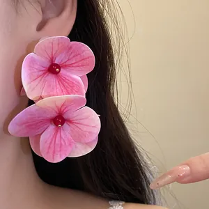 Close-up of sweet pink flower earrings on ear, showing fabric petal details for beach style.