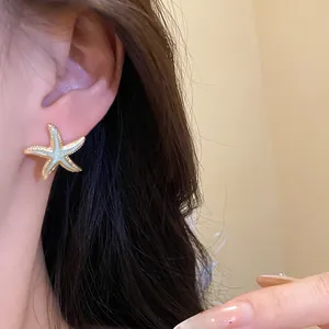 Detailed close-up view of a sweet blue starfish stud earring worn on a woman's ear