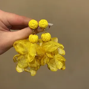 Close-up of yellow chiffon petal earrings with woven stud detail for bohemian style