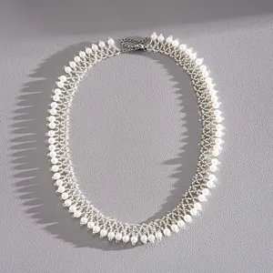 Vue détaillée du motif tissé complexe de ce tour de cou élégant en perles et perles d'argent