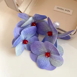 Elegant close-up of purple fabric floral earrings with white pearls and red beads accent