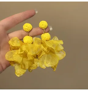 Close-up of vibrant yellow chiffon petal tassel earrings with woven bead detail