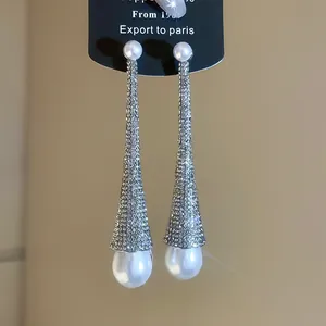 Close-up of luxury rhinestone teardrop earrings featuring elegant white pearls jewelry.