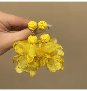 Macro detail of vibrant yellow chiffon petal tassel earrings for a bohemian holiday look