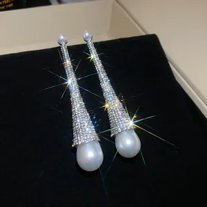 Close-up of luxury sparkling rhinestone tapered earrings with large teardrop pearls