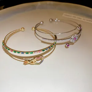 Vue détaillée de joncs plaqués or et argent 14K avec motifs de cœur et de fleur.