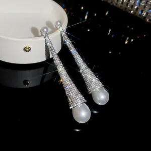 Close-up of sparkling rhinestone dangling earrings with elegant white teardrop pearls