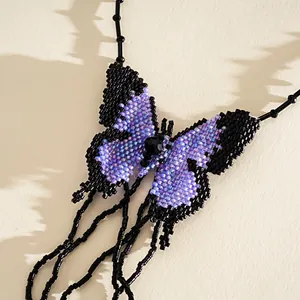 Macro detail of handmade beaded butterfly necklace with black and purple seed beads.