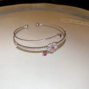 Gros plan d'un élégant bracelet jonc double couche plaqué or 14 carats avec fleur en zircon