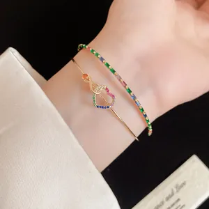 Gros plan montrant le détail d'un jonc plaqué or 14K et d'un bracelet cœur en zircon coloré