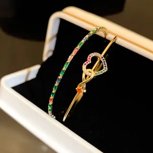 Détail de joncs dorés avec cœur et zircons multicolores présentés dans leur coffret