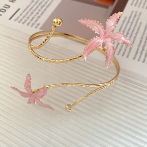 Gros plan détaillé d'un bracelet de bras étoile de mer rose émaillé avec anneau doré