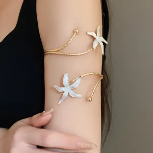 Vue détaillée d'un bracelet de bras en métal doré avec des étoiles de mer blanches.