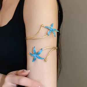 Bracelet de bras étoile de mer doré avec émail bleu porté sur le haut du bras.