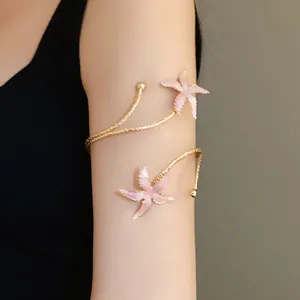 Gros plan d'un brassard doré avec deux étoiles de mer roses et finition émaillée.