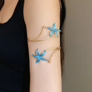 Détail d'un bracelet de bras doré orné de charmantes étoiles de mer en émail bleu