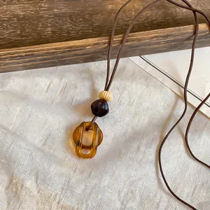Detail view of a vintage Maillard style amber resin geometric pendant on a long brown cord
