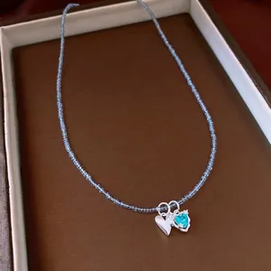 Elegant blue beaded necklace featuring double heart pendants displayed in a brown jewelry box