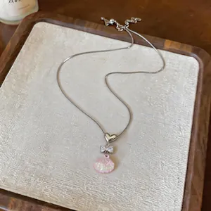 Detailed view of stainless steel heart bow and pink shell pendant necklace for women