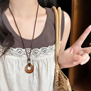 Detail of a retro amber resin circular pendant on a long brown cord necklace.