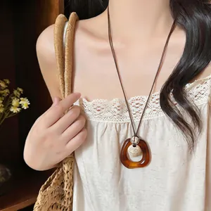 Vintage amber-colored resin geometric pendant necklace shown on a model wearing lace