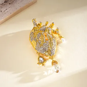 Close-up detail of a creative golden anatomical heart brooch with rhinestones and pearl charms