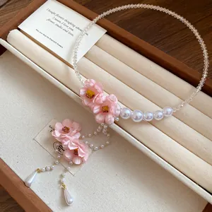 Primo piano del girocollo di perle in stile resort con fiori in tessuto rosa e nappe