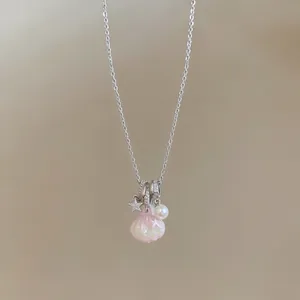 Close-up of silver chain necklace with pink seashell, pearl, and zircon star charms.