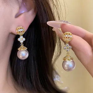 Elegant gold plated floral pearl dangle earrings featuring sparkling zirconia accents.