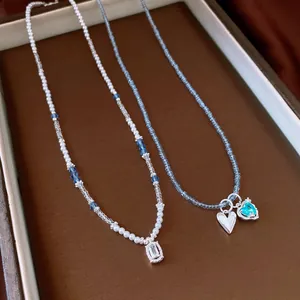 Detailed view of two elegant beaded necklaces featuring heart and crystal pendants on a tray