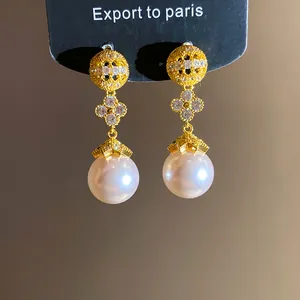 Close-up of 18k gold plated zircon flower earrings with large white pearl drops