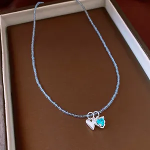 Detailed shot of a light blue beaded necklace with silver and cyan heart pendants
