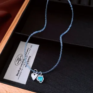 Close-up of light blue beaded necklace with silver and turquoise heart pendants