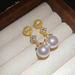 Macro detail of 18k gold plated pearl earrings with sparkling zircon flowers