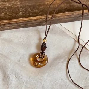 Close-up of vintage Maillard style amber geometric resin pendant necklace with brown cord