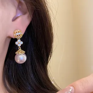 Detailed view of 18k gold plated pearl drop earrings with flower design on ear
