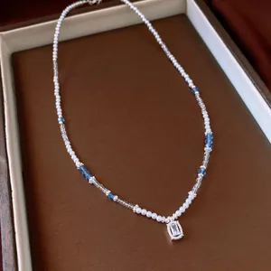Close-up detail of a beaded necklace featuring white pearls, blue crystals and gemstone