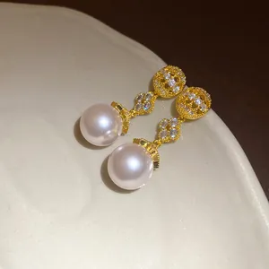 Close-up detail of 18k gold plated flower earrings with zircons and lustrous pearls