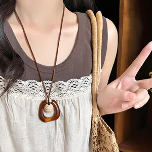 Detailed view of an amber geometric resin pendant on a vintage long brown cord necklace
