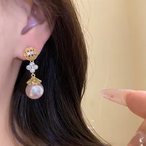 Close-up view of elegant 18k gold plated dangling earrings with zircon flower and pearl drop