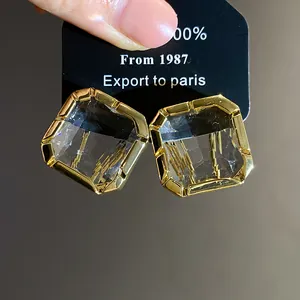 Close-up detail of square-cut clear crystal earrings set in a premium gold frame