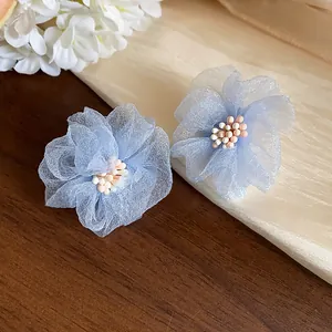 Primo piano di eleganti orecchini a lobo a fiore in chiffon azzurro con piccole perline.