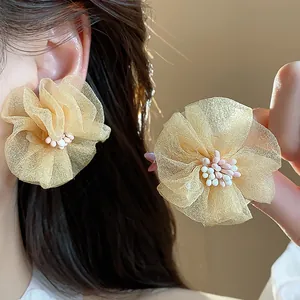 Primo piano di eleganti orecchini a fiore in chiffon color champagne
