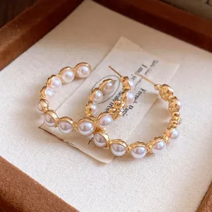 Détail de boucles d'oreilles créoles dorées vintage avec perles et strass élégants