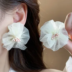 Dettaglio di eleganti orecchini a fiore in chiffon bianco con delicati pistilli rosa
