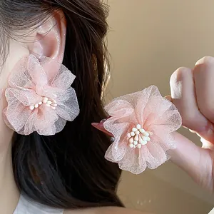 Primo piano di orecchini a lobo a fiore in chiffon rosa con centro di perline