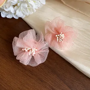Primo piano di dolci orecchini a lobo a fiore in chiffon rosa con petali delicati.