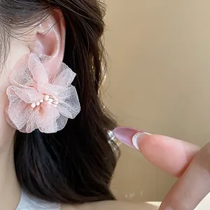 Primo piano di orecchini a fiore in chiffon rosa con petali in rete e centro di perle.