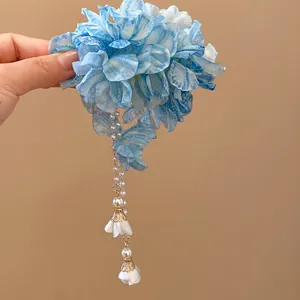 Detail view of an ethereal blue bohemian fabric flower hair clip with elegant pearl tassels